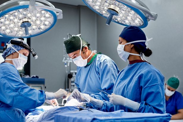 Female surgeon operating patient at table. Medical professionals are working in emergency room. They are wearing scrubs.